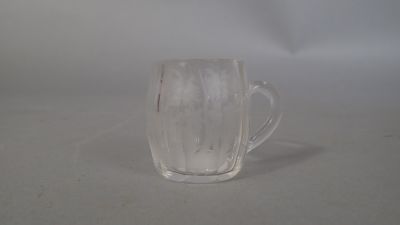 un verre en verre transparent muni d'une anse, posé sur une table