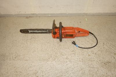 an orange chainsaw sitting on the floor next to a white wall