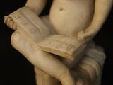 a statue of a child reading a book on a bench