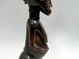 statue d'une femme assise sur un tabouret, coiffée d'un chapeau