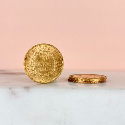a gold coin sitting next to a gold coin on a marble surface