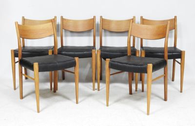 four wooden chairs with black leather seats against a white wall