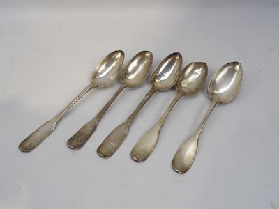six cuillères en argent sont alignées sur une surface blanche