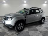La Dacia argentée est garée dans une grande pièce au sol carrelé en damier.