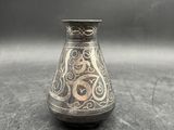 un vieux vase en argent orné d'un motif, posé sur une table