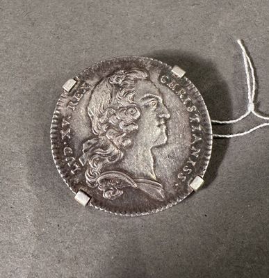 une vieille pièce d'argent entourée d'une corde, posée sur une table