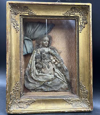 une sculpture antique en bronze représentant une femme tenant un bébé dans ses bras, dans un cadre doré