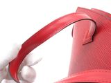 a hand holding a red purse with a red strap