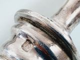 a close up of a silver object on a white surface
