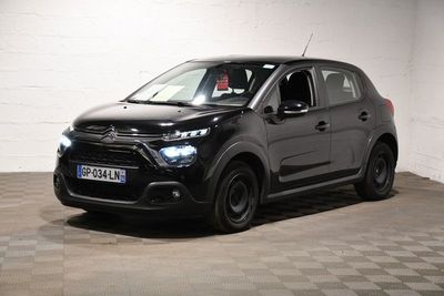 La petite voiture noire est garée dans le garage, sur le sol à damier.