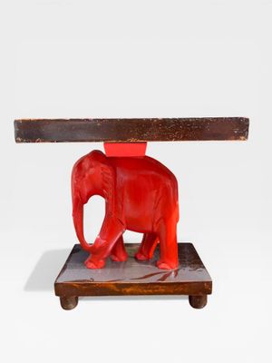 un éléphant rouge qui se tient debout sous une table