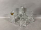 trois bouteilles en verre transparent et une petite bouteille en verre posées sur une surface blanche