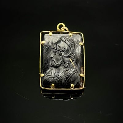 un pendentif noir et doré représentant une femme de profil