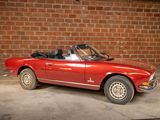 an image of a red convertible car parked in front of a brick wall