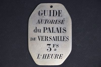 silver plate with the words guide autorise du palais de versailles 75°s l ' heure written on it