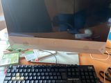 un écran d'ordinateur et un clavier posés sur un bureau, à côté d'un téléphone portable