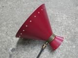 une image représentant une lampe rouge ornée d'étoiles, posée sur un sol en béton