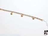 un gros plan d'un bracelet orné de breloques dorées sur fond blanc