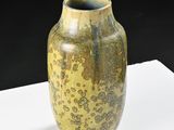 a yellow vase sitting on a white table with a black background