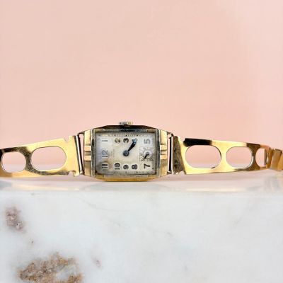 une photo d'une montre-bracelet en or posée sur une table en marbre