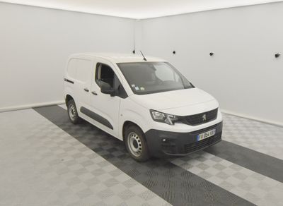 La camionnette blanche est garée dans une pièce propre dont le sol est recouvert d'un carrelage à damier noir et blanc.