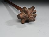 a small metal object with a wooden handle on a white surface