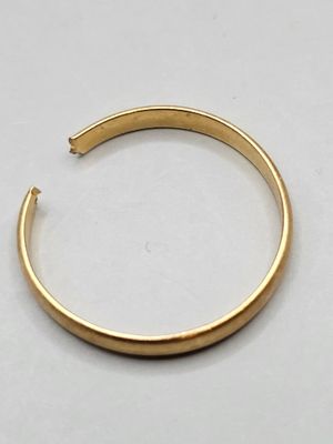 gros plan d'un bracelet en or sur une surface blanche