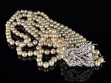 a close up of a necklace with pearls on a black surface