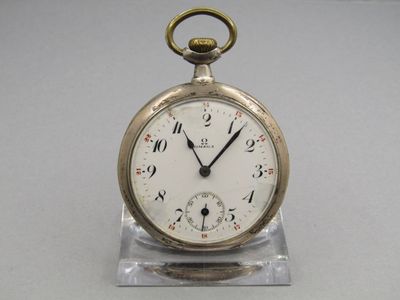 a silver pocket watch sitting on a clear stand