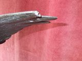 une statue représentant un oiseau, posée sur un mur rouge