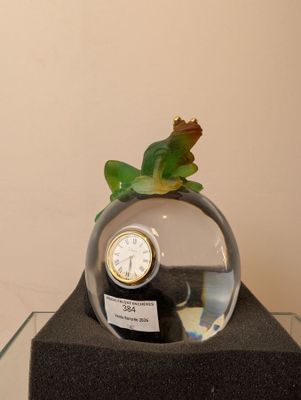 une petite plante dans un vase en verre orné d'une horloge