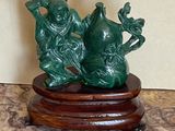 une statue verte représentant deux personnes assises sur un socle en bois