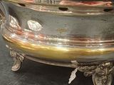 a silver bowl on a stand on a table