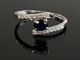 an image of a diamond and sapphire ring on a black surface