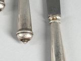 three silver plated knives and a knife holder on a white surface