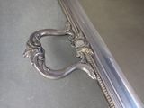 a silver mirror with a handle on the floor