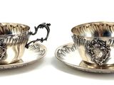 pair of silver plated tea cups and saucers on a saucer