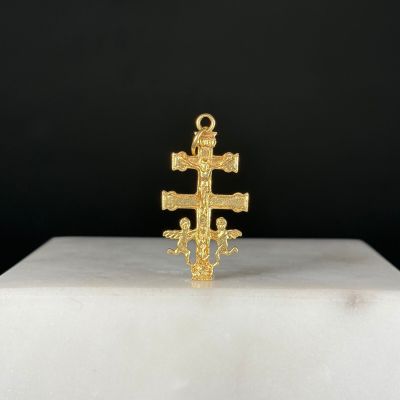 un gros plan d'une croix en or posée sur un socle blanc