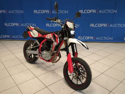 a red and white motorcycle parked in front of a blue wall