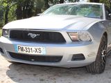 a silver mustang parked on the side of the road