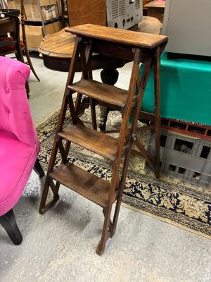 une chaise rose et un tabouret en bois dans une pièce