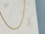 un gros plan d'un collier à chaîne en or posé sur une surface en marbre