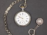 une montre de poche en argent avec une chaîne autour d'elle