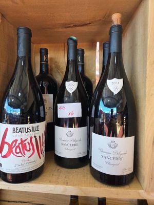 Plusieurs bouteilles de vin sont posées dans une caisse en bois sur une étagère
