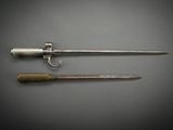 two swords and a knife on a table with a gray background