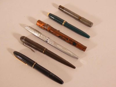 Plusieurs stylos sont alignés en rangée sur une surface blanche