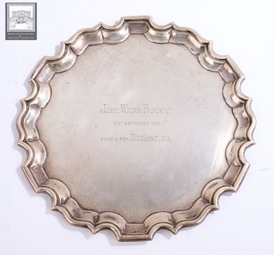 an antique silver plate with writing on it sitting on a white surface
