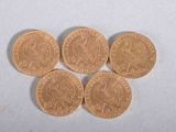 four gold coins sitting on top of each other on a white surface