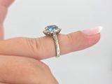 a woman ' s hand holding a ring with a blue stone on it