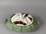 a green and white bowl with cherries in it